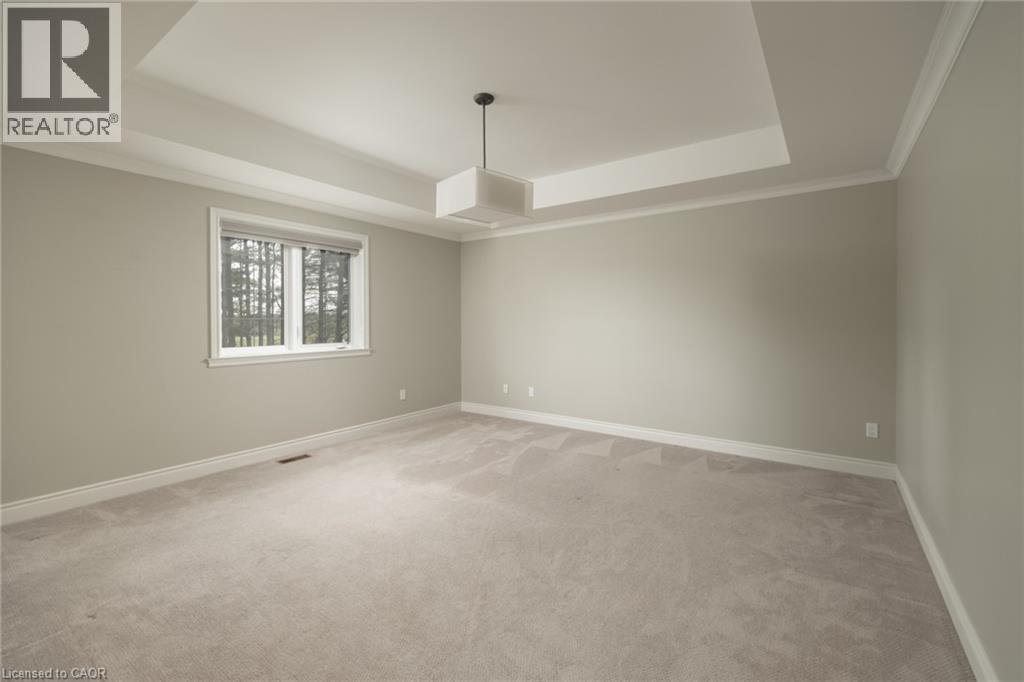 Recessed tray ceiling, neutral wall color, crown molding, window with outdoor scenery, and light-colored carpeting - 1505 Milburough Line, Carlisle, ON
