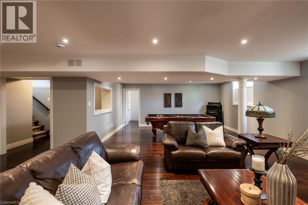 Spacious recreation area featuring wood-finish flooring, recessed lighting, and a prominent architectural column - 1505 Milburough Line, Carlisle, ON