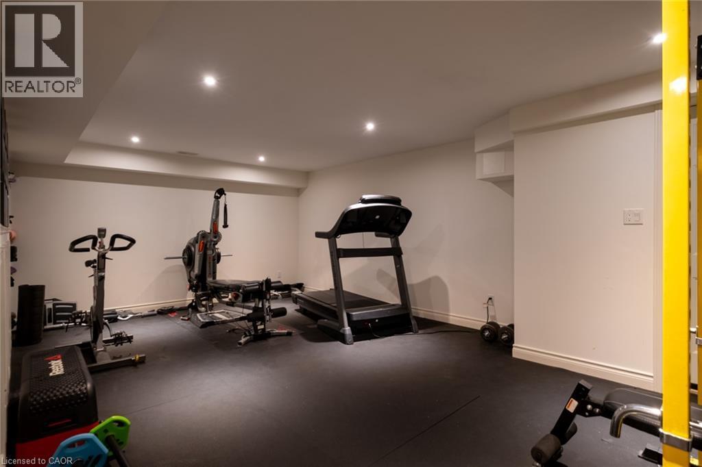 Recessed ceiling lighting illuminates a spacious room featuring a dark rubber-finish floor and white painted walls - 1505 Milburough Line, Carlisle, ON