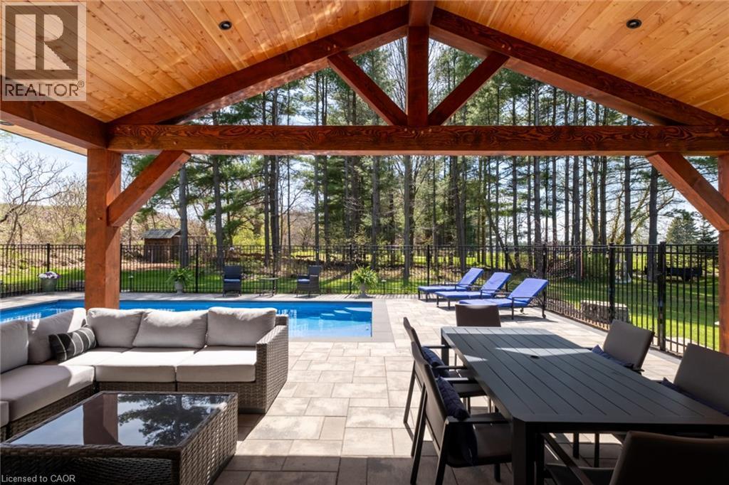 Covered outdoor living space featuring a wood-beam ceiling, exposed structural timbers, and recessed lighting - 1505 Milburough Line, Carlisle, ON