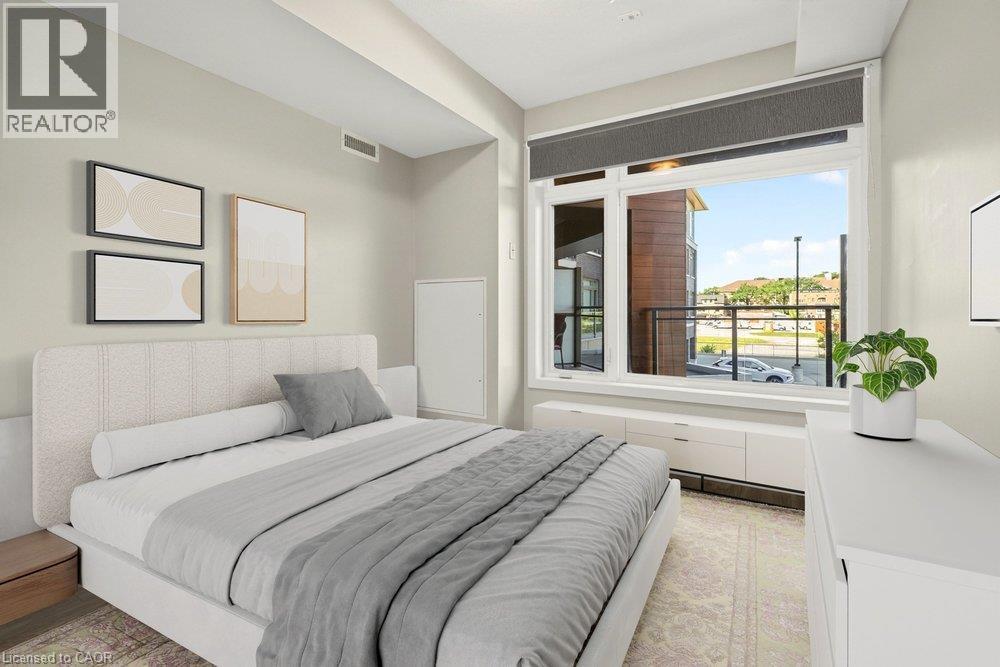 Spacious room featuring a large window, a built-in window bench with storage, textured light-colored walls, wood-finish flooring, and a white ceiling - 457 Plains Road Unit# 225, Burlington, ON