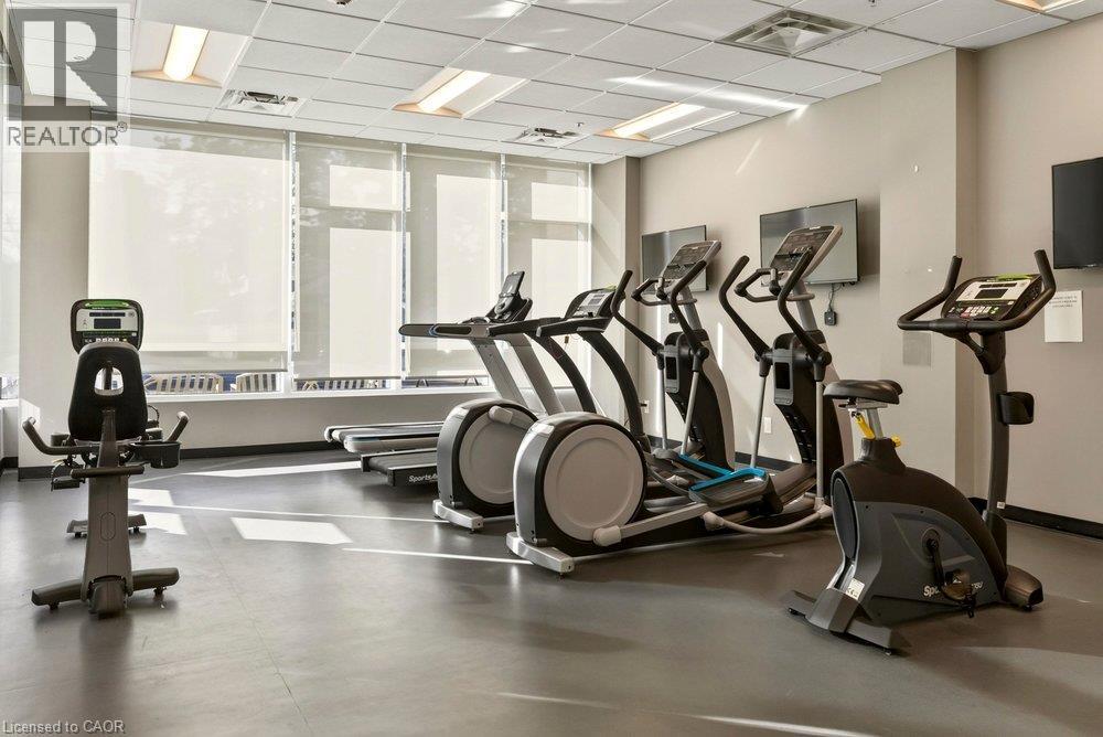 Fitness center with multiple cardio machines, television screens, recessed lighting, and large windows with roller shades - 457 Plains Road Unit# 225, Burlington, ON