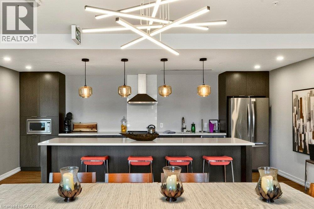 Kitchen featuring dark wood-finish cabinetry, stainless steel appliances, and a central island with white countertops - 457 Plains Road Unit# 225, Burlington, ON