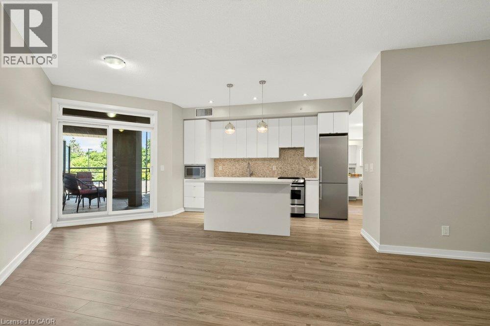 Open-concept living space featuring wood-finish flooring and light-toned walls - 457 Plains Road Unit# 225, Burlington, ON