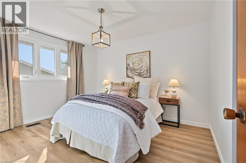 PRIMARY BEDROOM with NEW vinyl flooring, large closet, vinyl windows & elegant new light fixture. - 589 Mohawk Road W, Hamilton, ON