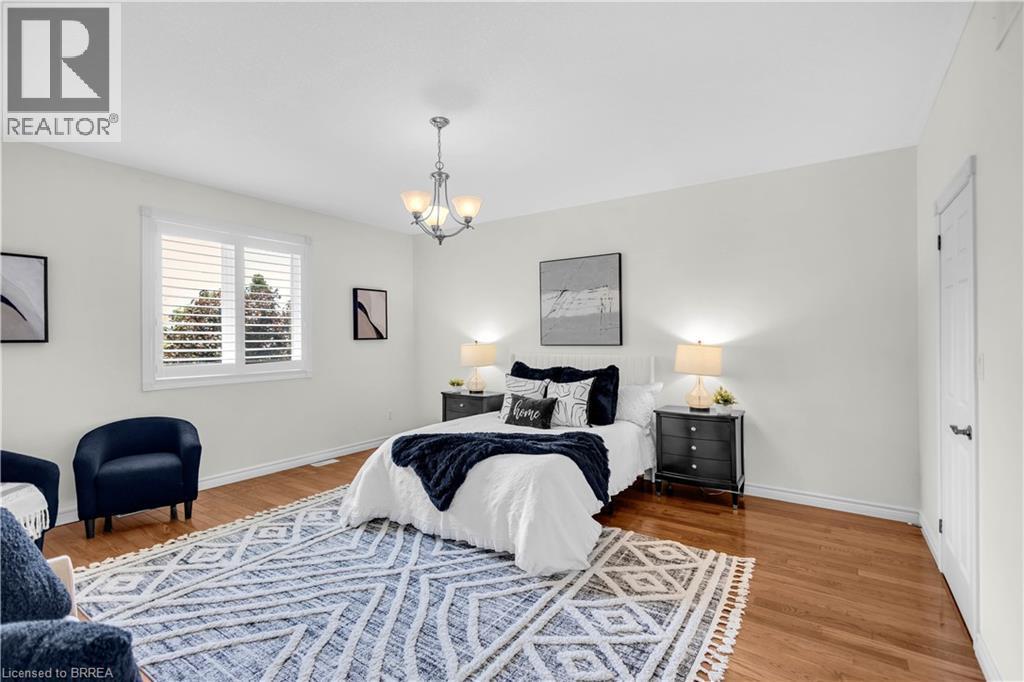 Room featuring wood-finish flooring, a contemporary chandelier, white walls, and a window with white plantation shutters - 302 German School Road, Paris, ON