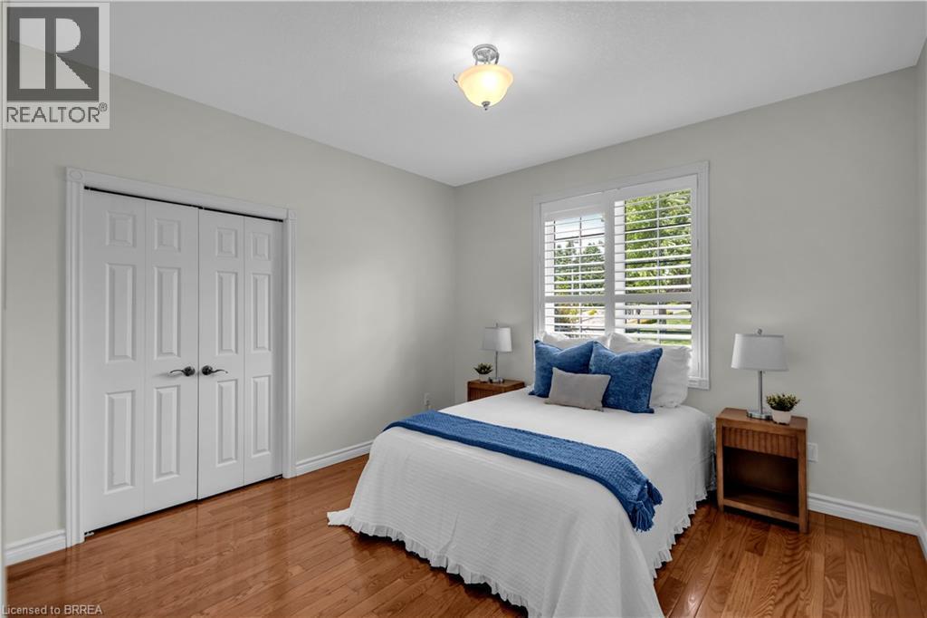 Room featuring wood-finish flooring, a double window with plantation shutters, ceiling-mounted lighting, and a bi-fold closet - 302 German School Road, Paris, ON