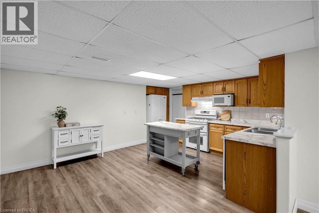 Kitchen featuring wood-finish cabinetry, white tile backsplash, and stone-look countertops - 302 German School Road, Paris, ON