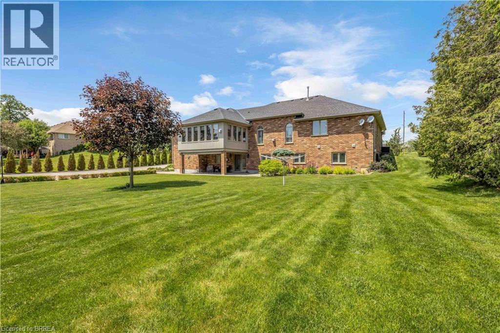 Expansive rear lawn featuring a mature tree and landscaped beds - 302 German School Road, Paris, ON
