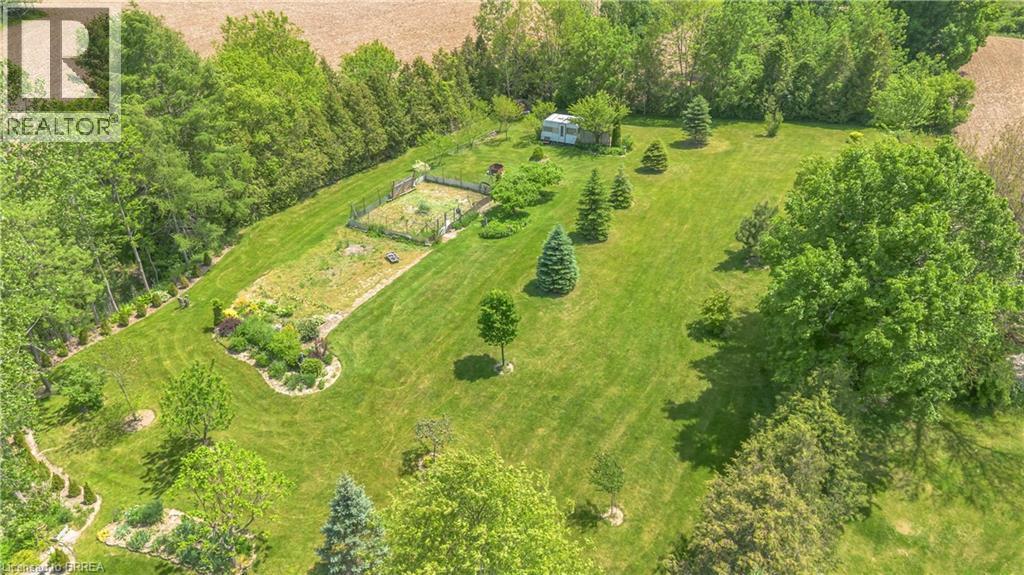 Expansive green space featuring mature trees, manicured lawns, and established garden beds - 302 German School Road, Paris, ON