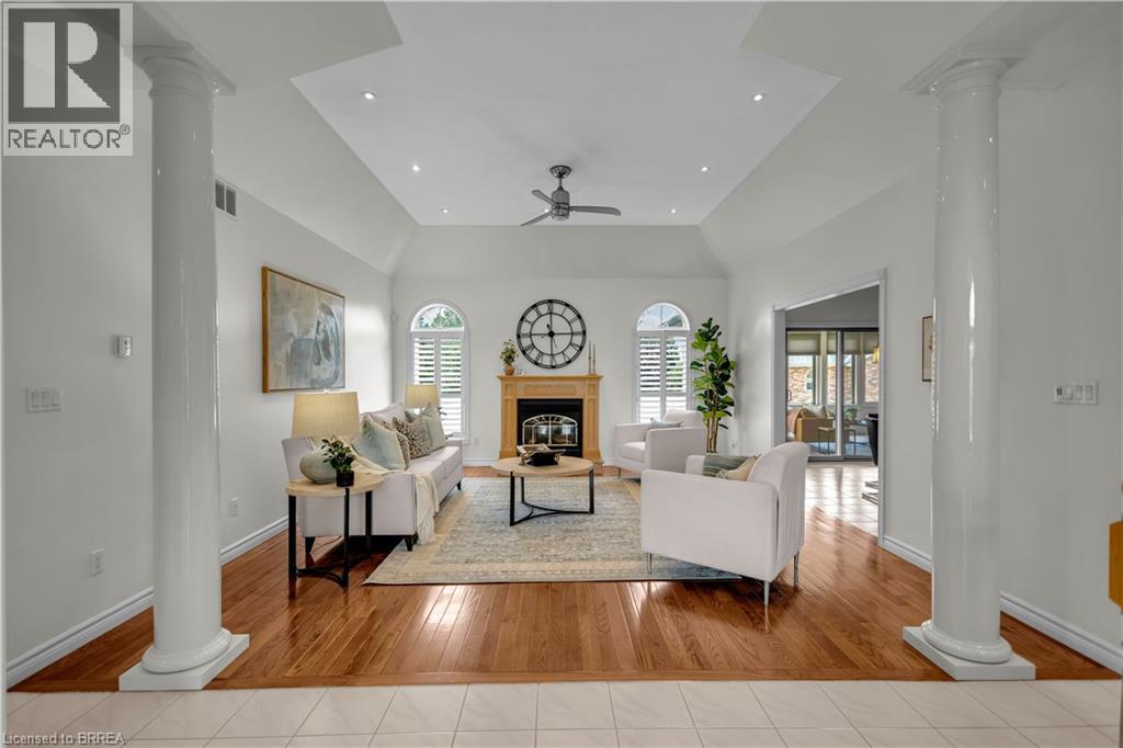 Living area featuring hardwood flooring, an arched fireplace with a wood mantle, vaulted ceilings with recessed lighting, and a ceiling fan - 302 German School Road, Paris, ON