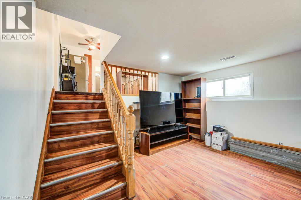 Wood-finish flooring, wood staircase with light wood railing, recessed lighting, and a horizontal window - 143 Sunrise Place, Kitchener, ON