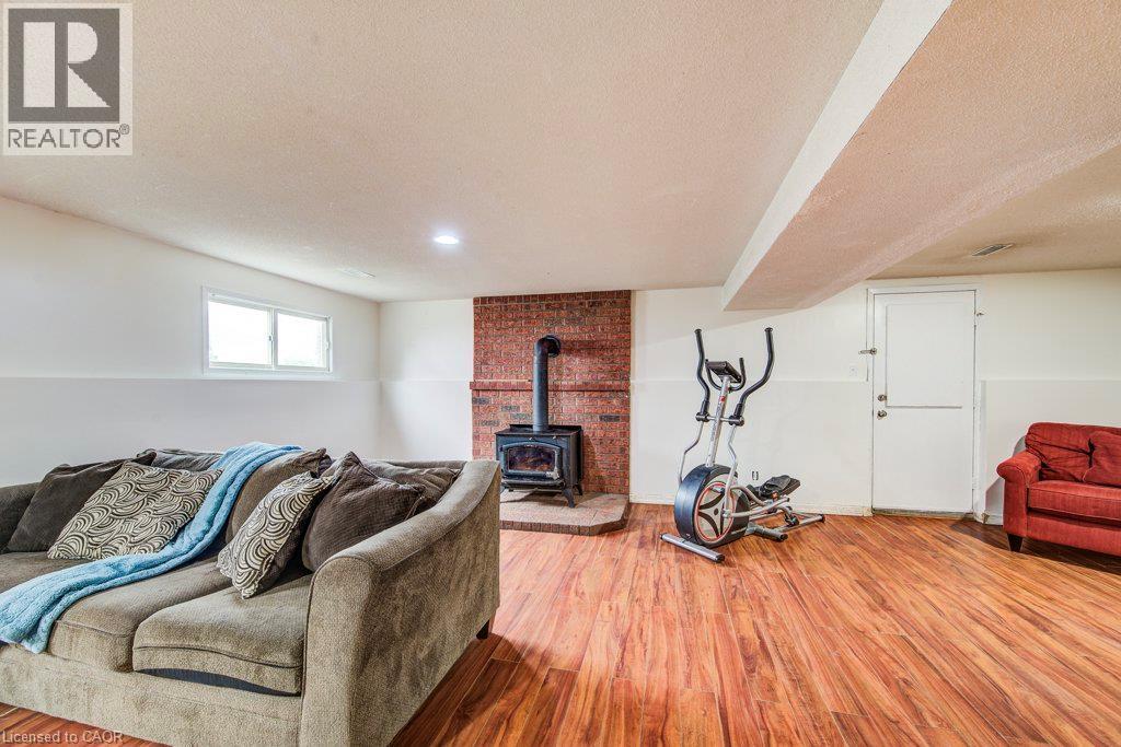 Wood-finish flooring, white walls, and a brick-faced fireplace with a wood-burning stove - 143 Sunrise Place, Kitchener, ON
