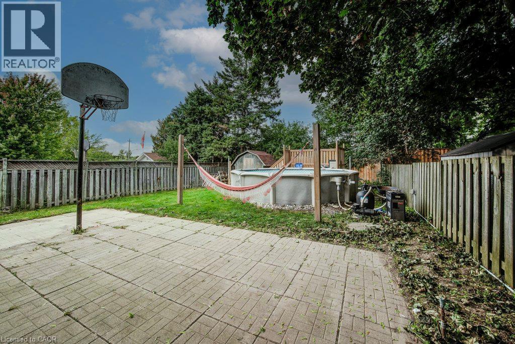 Expansive backyard featuring a patterned paver patio, a basketball hoop, an above-ground pool, and a storage shed - 143 Sunrise Place, Kitchener, ON