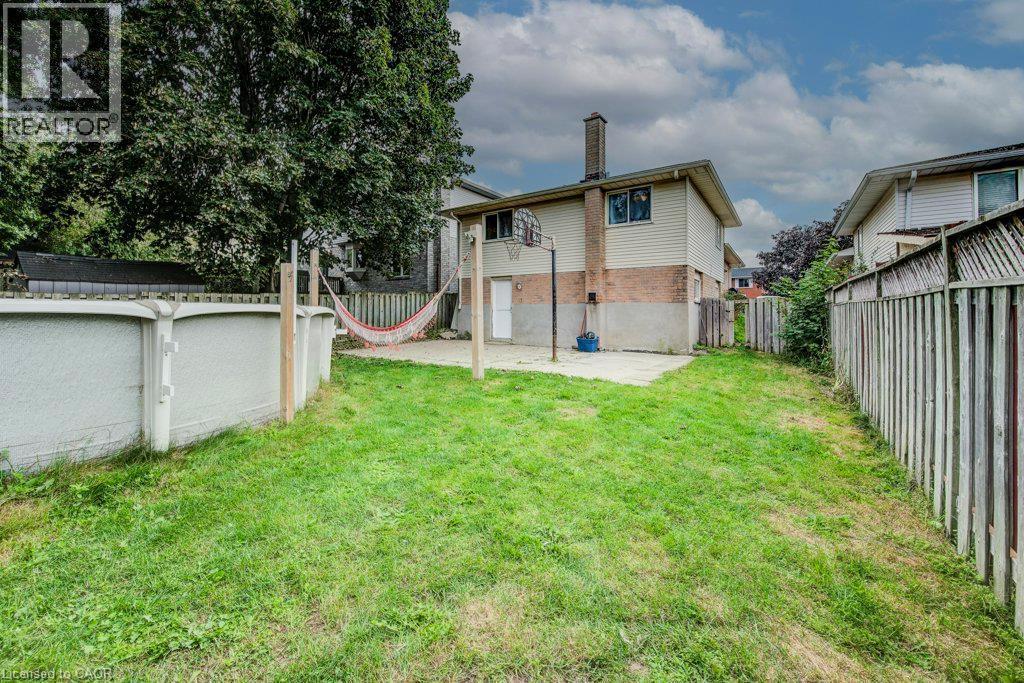 Expansive grassy yard with an above-ground pool, concrete patio, and fenced perimeter - 143 Sunrise Place, Kitchener, ON