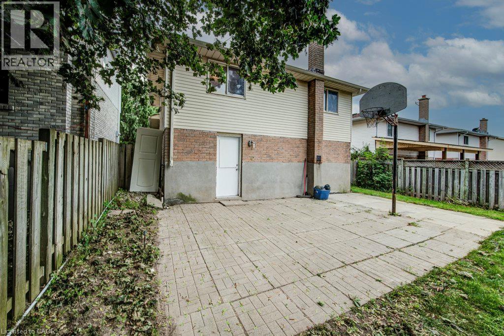 Paved patio area with direct exterior access, brick and siding exterior, and a privacy fence - 143 Sunrise Place, Kitchener, ON