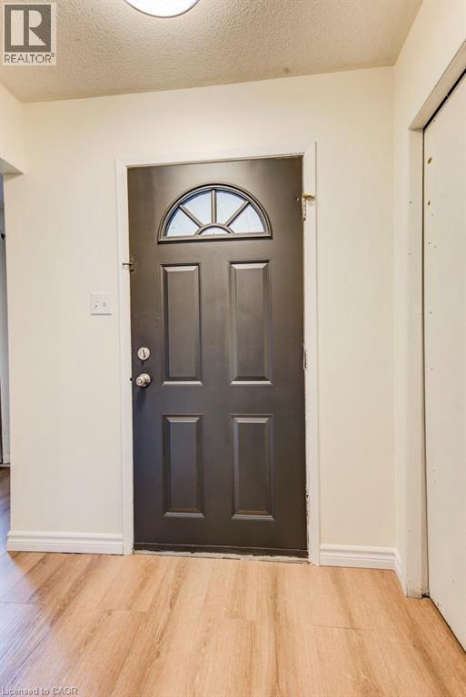 Entry door with an arched transom window, paneled design, and wood-finish flooring - 143 Sunrise Place, Kitchener, ON