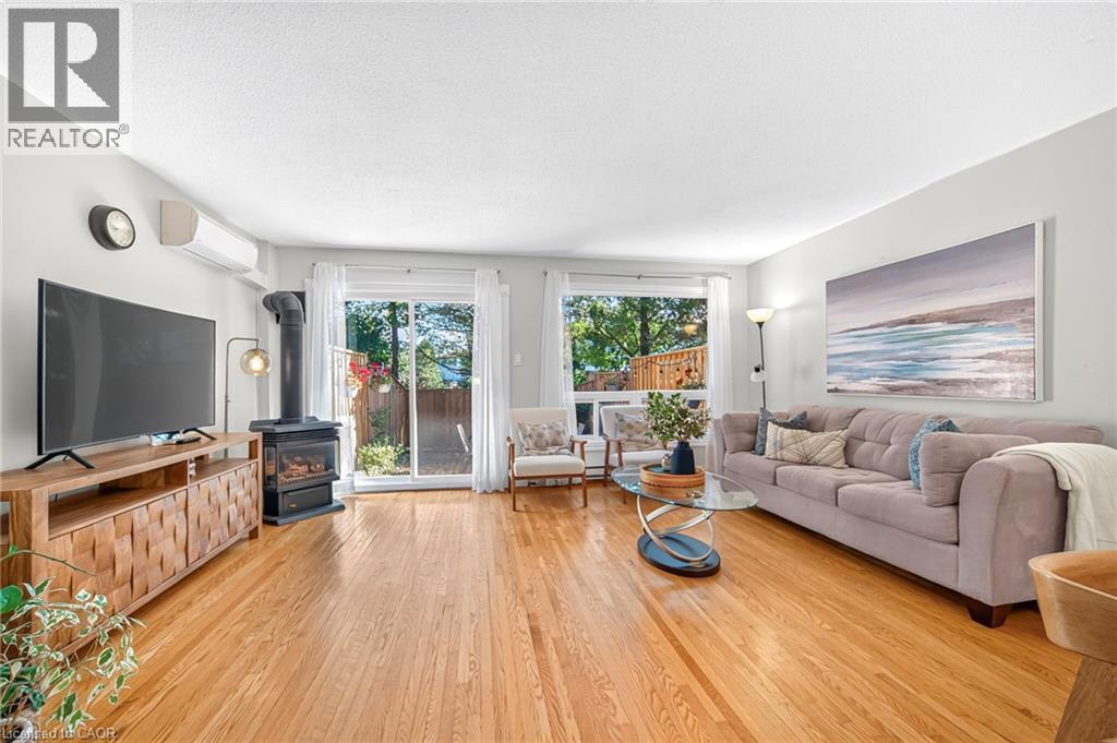 Hardwood flooring, wood-burning stove, sliding glass door, window, and wall-mounted air conditioning unit - 1517 Elm Road Unit# 9, Oakville, ON