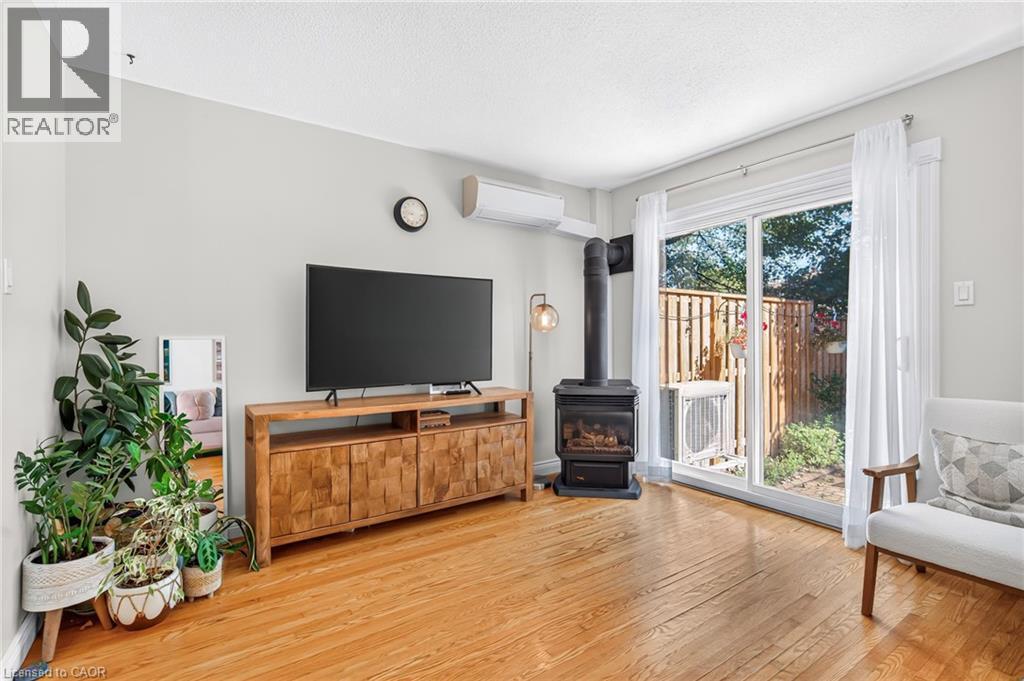 Hardwood flooring, sliding glass door leading to an outdoor area, a built-in wood-burning stove, and a wall-mounted air conditioning unit - 1517 Elm Road Unit# 9, Oakville, ON