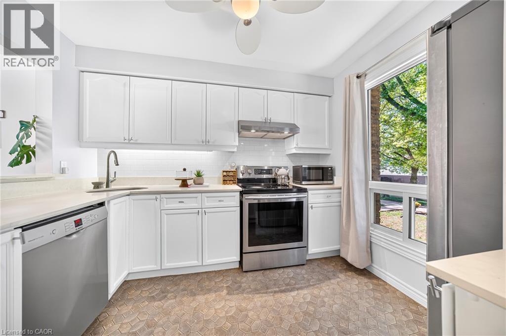 Kitchen featuring white cabinetry, light-colored countertops, stainless steel appliances, and a mosaic tile floor - 1517 Elm Road Unit# 9, Oakville, ON