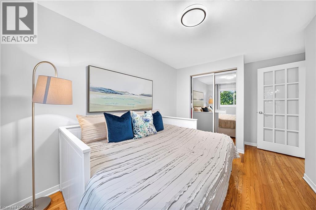 Hardwood flooring, sliding mirrored closet doors, recessed ceiling light fixture, white interior door with glass inserts, and white wall finishes - 1517 Elm Road Unit# 9, Oakville, ON