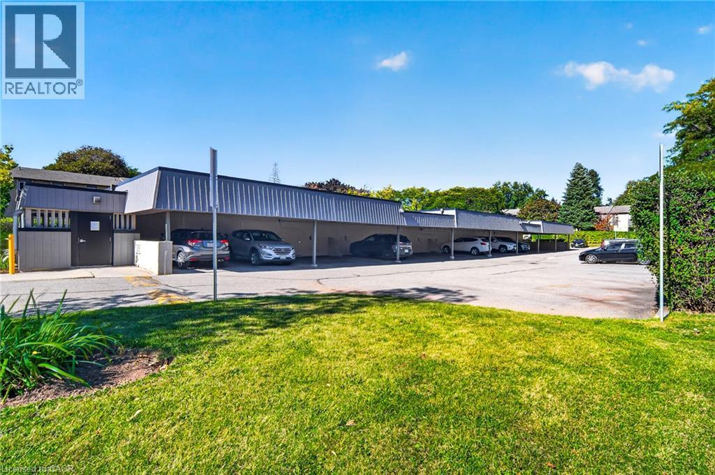Paved parking area with covered parking structures and surrounding green space - 1517 Elm Road Unit# 9, Oakville, ON