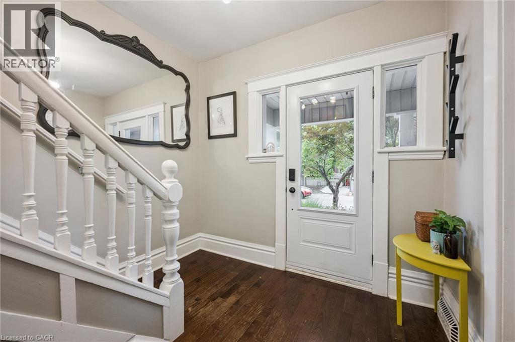 Hardwood flooring, white paneled entry door with glass inserts, white framed sidelight windows, and white painted staircase with balusters - 58 Balmoral Avenue N, Hamilton, ON