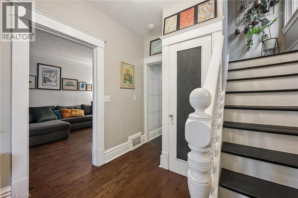 Hardwood flooring, white trim, traditional staircase with dark treads, closet. - 58 Balmoral Avenue N, Hamilton, ON