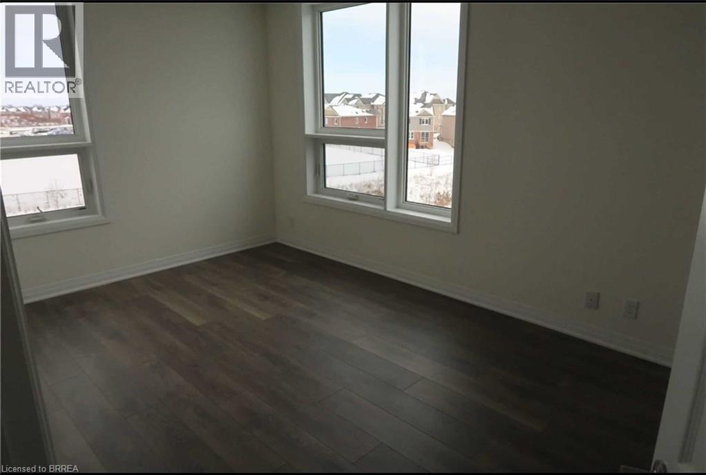 Unfurnished room featuring dark wood-type flooring and plenty of natural light - 1105 Leger Way Unit# 329, Milton, ON