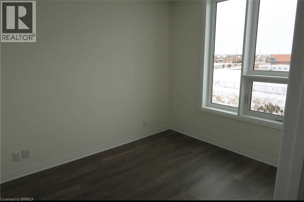 Empty room with baseboards and dark wood-type flooring - 1105 Leger Way Unit# 329, Milton, ON