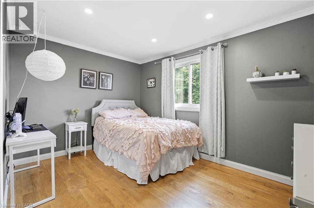 Spacious room featuring wood-finish flooring, recessed lighting, and a window with white trim - 72 Crestlynn Crescent, Simcoe, ON
