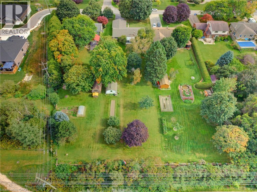 Expansive green lawn with mature trees, multiple garden beds, and two outbuildings - 15 Mclaren Avenue N, Listowel, ON