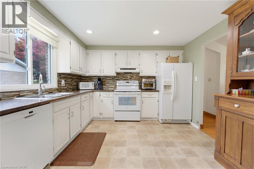 White cabinetry, stainless steel sink, tiled backsplash, and recessed lighting - 15 Mclaren Avenue N, Listowel, ON