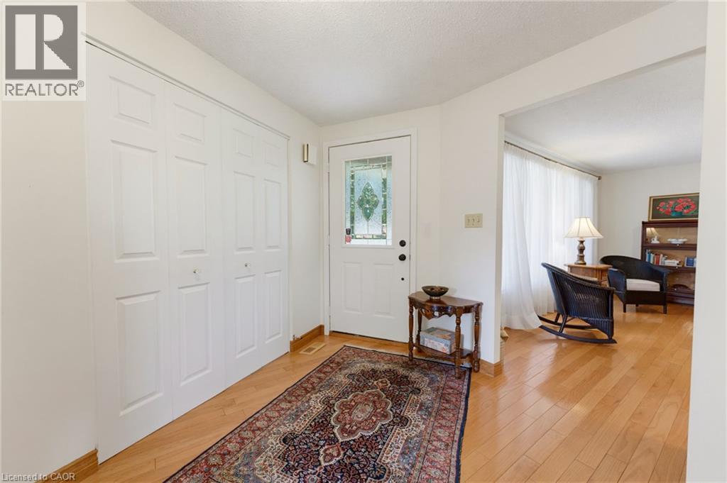 Entryway featuring light wood-finish flooring, white paneled bi-fold closet doors, and a front door with decorative glass inserts - 15 Mclaren Avenue N, Listowel, ON