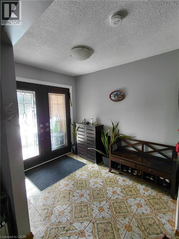 Patterned tile flooring, double entry doors with decorative glass panels, and a flush mount ceiling light fixture - 244 Guildwood Drive, Hamilton, ON