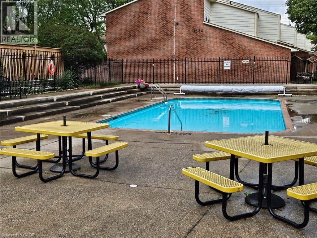 Outdoor swimming pool with surrounding concrete patio and perimeter fencing - 1548 Newlands Crescent Unit# 14, Burlington, ON