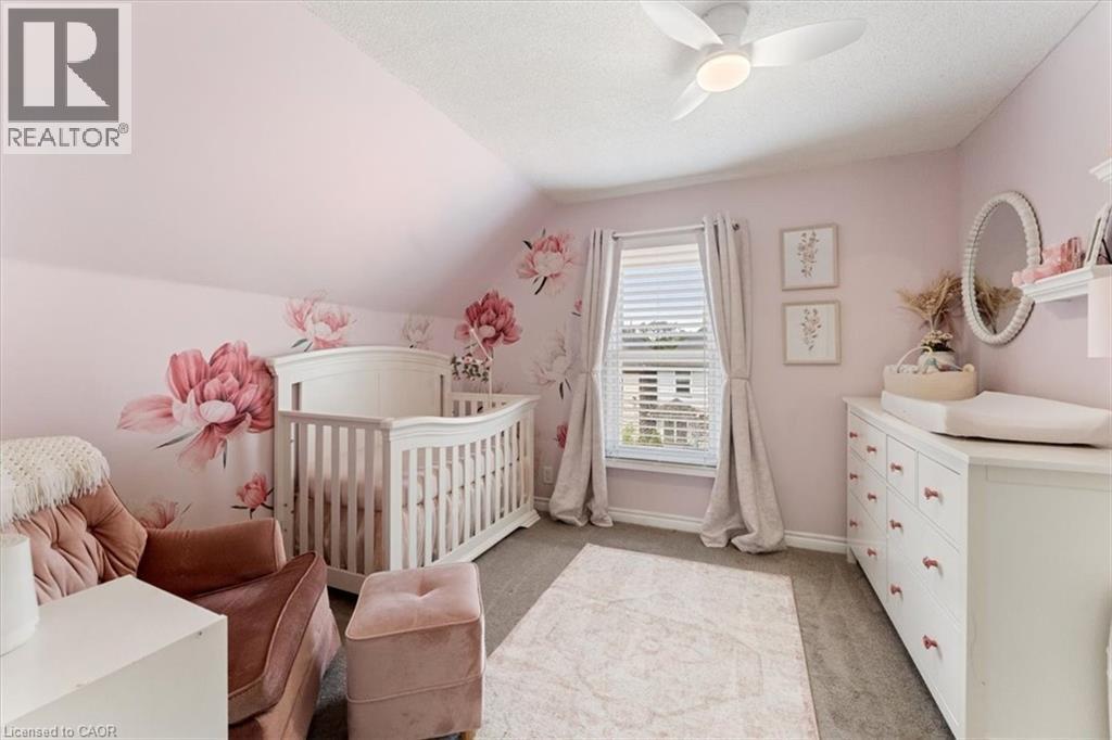 Carpeted room with sloped ceilings and a window featuring white blinds and neutral drapes - 17 Craigmiller Avenue, Hamilton, ON
