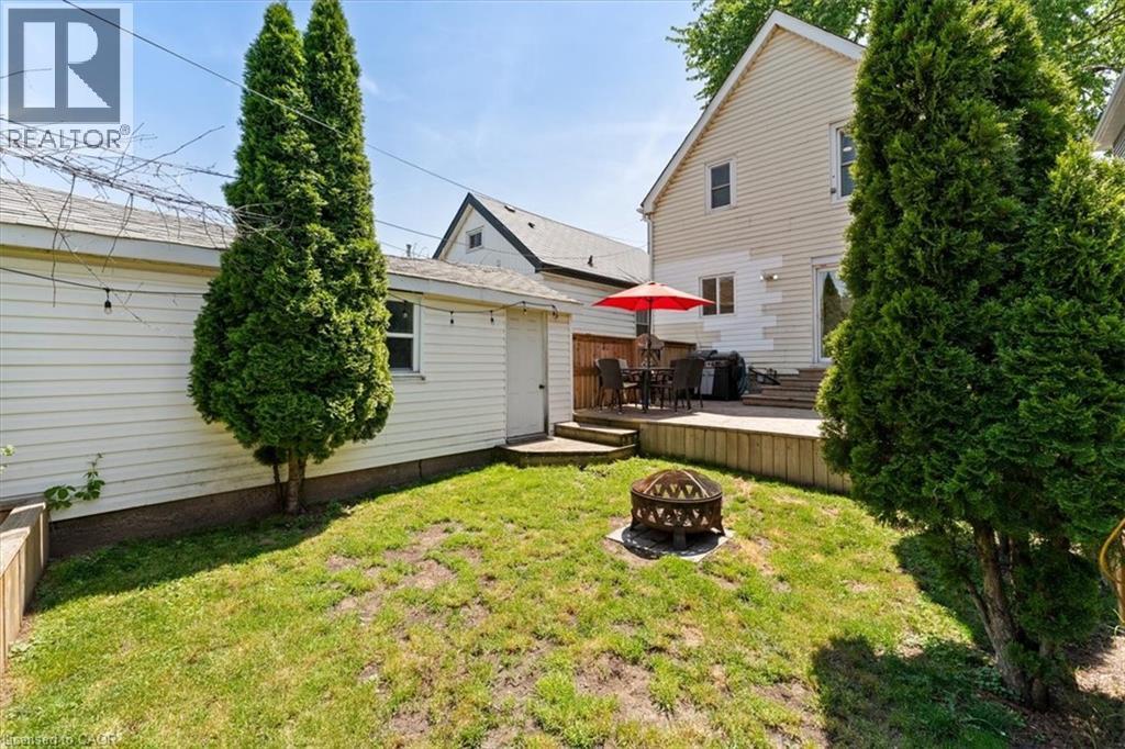 Expansive backyard featuring a manicured lawn, a fire pit, and mature trees - 17 Craigmiller Avenue, Hamilton, ON