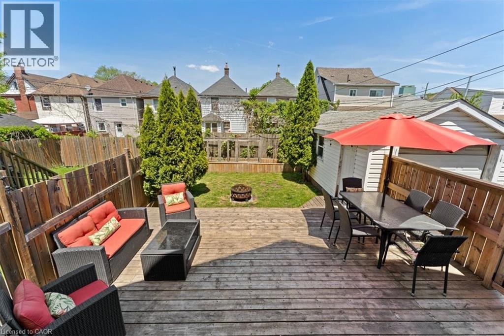 Expansive backyard featuring a multi-level wood deck, a grass lawn, and mature privacy trees - 17 Craigmiller Avenue, Hamilton, ON