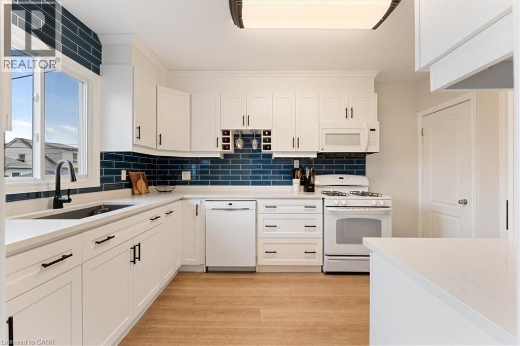 White kitchen featuring shaker-style cabinetry, a built-in wine rack, and a deep blue subway tile backsplash - 17 Craigmiller Avenue, Hamilton, ON
