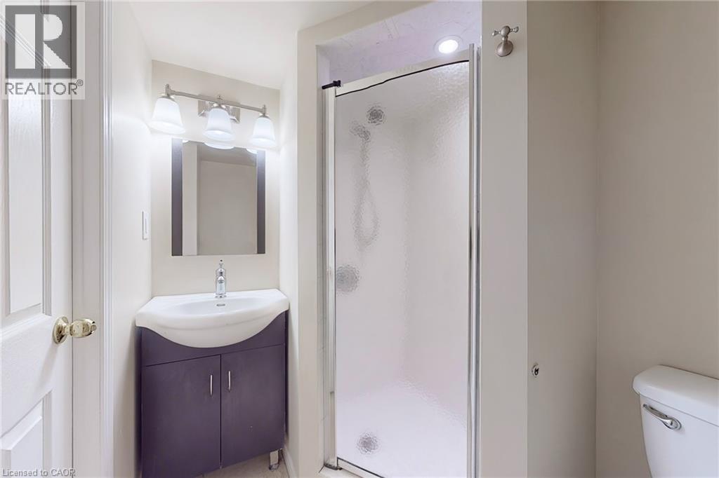 Bathroom featuring a corner vanity with integrated sink, framed mirror, three-light vanity fixture, and a glass-enclosed shower - 21 Eastview Gate Unit# 36, Brampton, ON