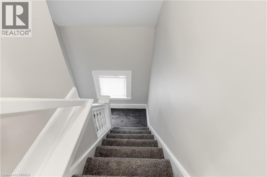 Carpeted staircase with white painted railing and balusters, featuring a dormer window with a white frame - 87 Strathcona Avenue, Brantford, ON