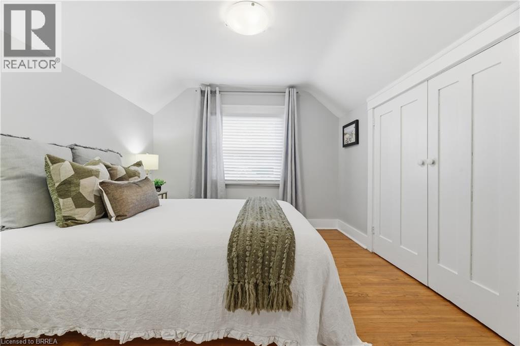 Hardwood flooring, painted paneled double closet doors, window with blinds and drapes, and a ceiling-mounted light fixture - 87 Strathcona Avenue, Brantford, ON
