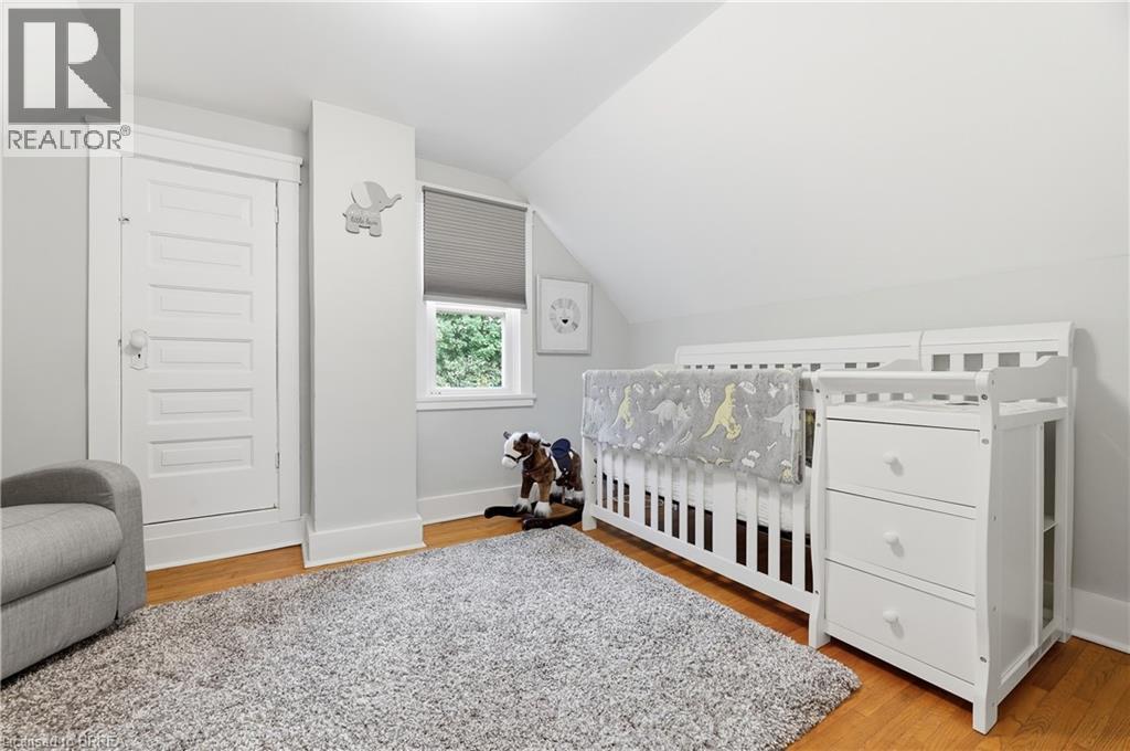 Wood-finish flooring with white trim, window with privacy blind, and a white paneled door - 87 Strathcona Avenue, Brantford, ON
