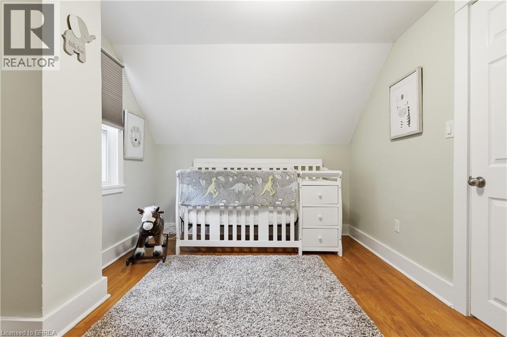 Wood-finish flooring, white trim, window with blinds, and a paneled door - 87 Strathcona Avenue, Brantford, ON