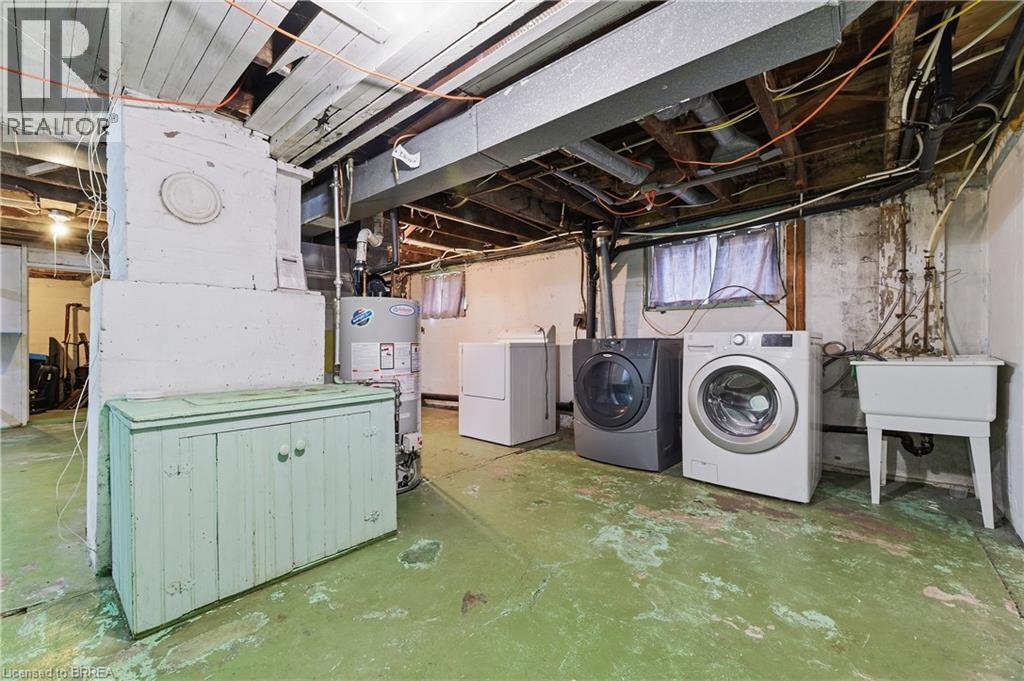 Basement utility space featuring a water heater, laundry appliances, and a utility sink - 87 Strathcona Avenue, Brantford, ON
