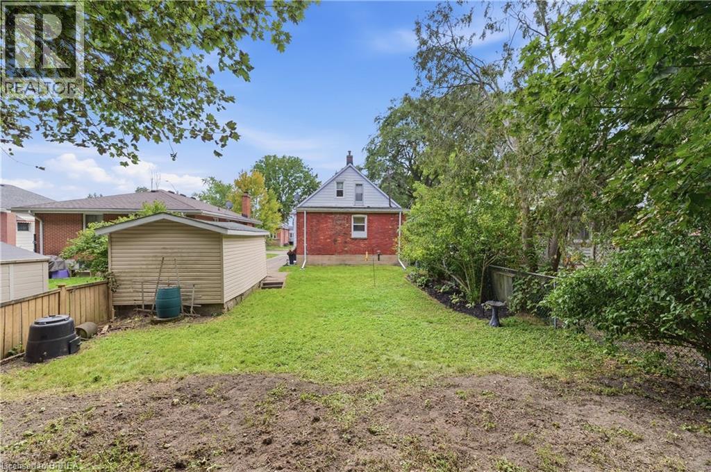 Expansive backyard featuring a manicured lawn, established landscaping, and a detached shed - 87 Strathcona Avenue, Brantford, ON