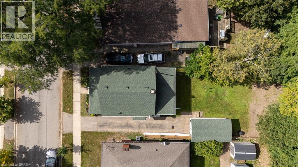 Gable roof residence featuring a front yard, a side driveway, and a rear yard with green space - 87 Strathcona Avenue, Brantford, ON
