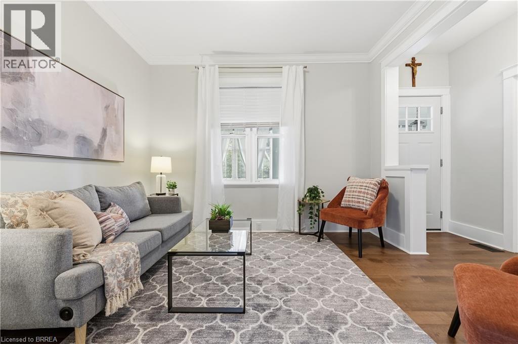 Hardwood flooring, white window trim, white crown molding, recessed entry door with transom window, and a half-wall partition - 87 Strathcona Avenue, Brantford, ON