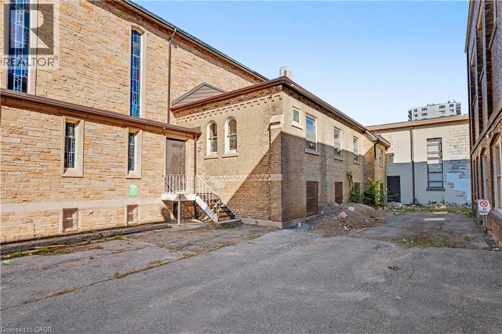 Multi-level brick exterior with arched windows, stained glass features, and an exterior staircase - 97 Wellington Street, Brantford, ON